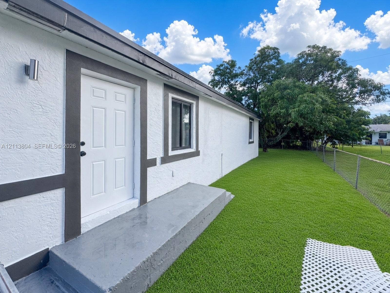 2300 NW 31st Avenue, Fort Lauderdale, FL 33311 Exterior elevation featuring textured stucco siding, contrast trim, a concrete step, and a fenced-in grassy yard