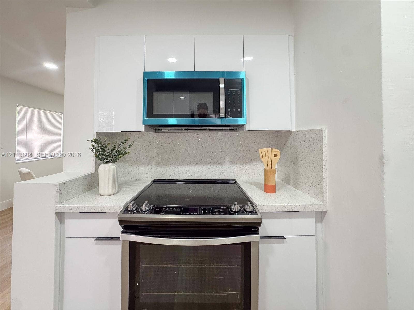 2300 NW 31st Avenue, Fort Lauderdale, FL 33311 Gloss-finish white cabinetry featuring flat-panel doors, stone-composite countertops, high-back matching backsplash, stainless steel electric range, and over-the-range microwave