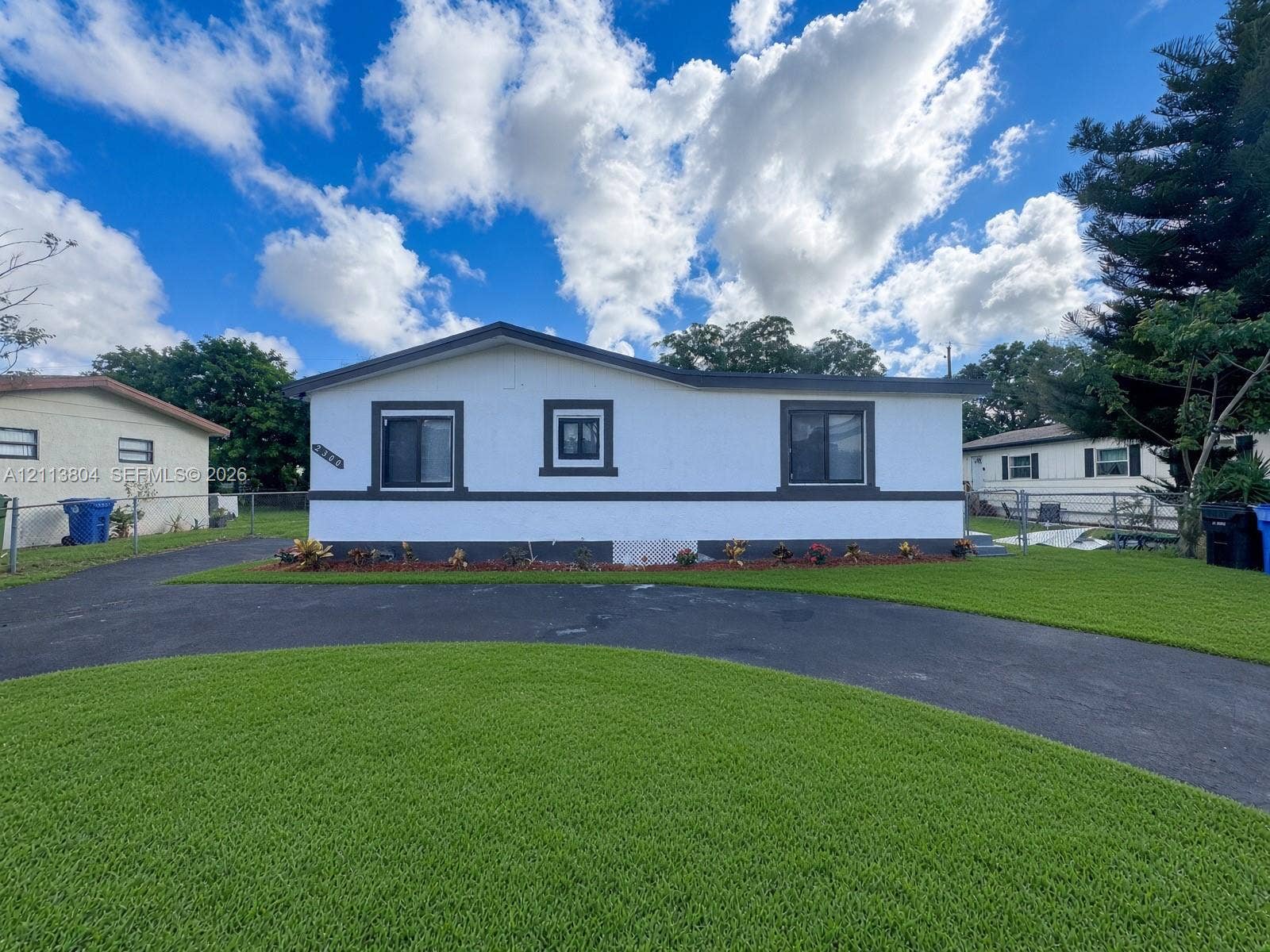 2300 NW 31st Avenue, Fort Lauderdale, FL 33311 Single-story exterior featuring white stucco finish, contrasting dark trim, manicured lawn, and asphalt driveway