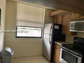 1516 Whitehall Drive, #204, Davie, FL 33324 Kitchen featuring wood cabinetry, stainless steel appliances, and a window with horizontal blinds