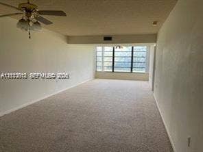 1516 Whitehall Drive, #204, Davie, FL 33324 Expansive interior area featuring neutral wall-to-wall carpeting, a multi-blade ceiling fan with integrated light fixture, and large-scale windows with black frames
