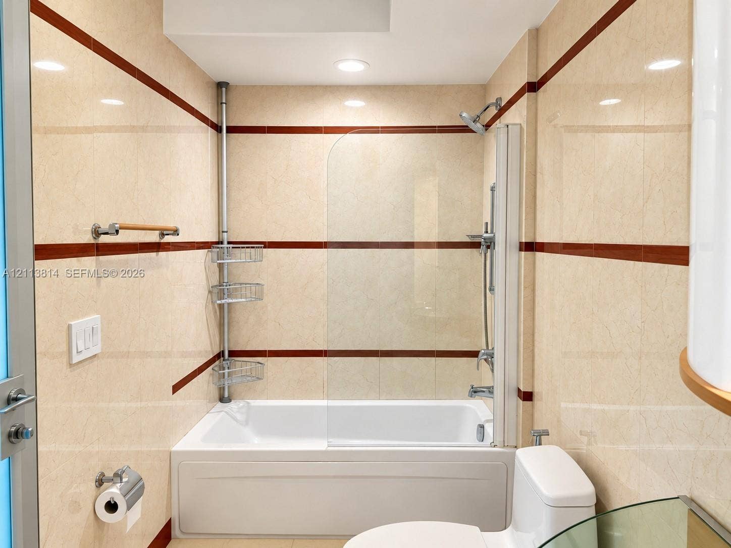 110 Washington Avenue, #1517, Miami Beach, Miami Beach, FL 33139 Bathroom featuring a full-sized bathtub with a glass splash panel, dual-finish wall tiling with integrated accent stripes, adjustable shower head, and recessed lighting