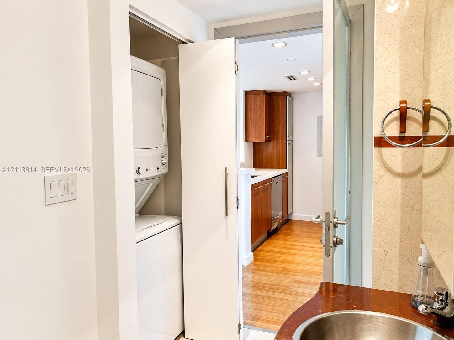 110 Washington Avenue, #1517, Miami Beach, Miami Beach, FL 33139 Enclosed laundry closet with stacked appliance unit, vanity featuring a metallic basin, and wood-finish flooring