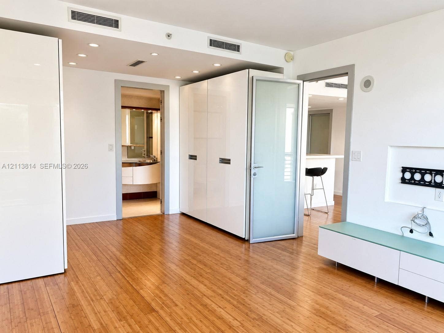 110 Washington Avenue, #1517, Miami Beach, Miami Beach, FL 33139 Interior space featuring light wood-finish flooring, high-gloss white built-in cabinetry, recessed ceiling lighting, and a frosted glass door with a metal frame
