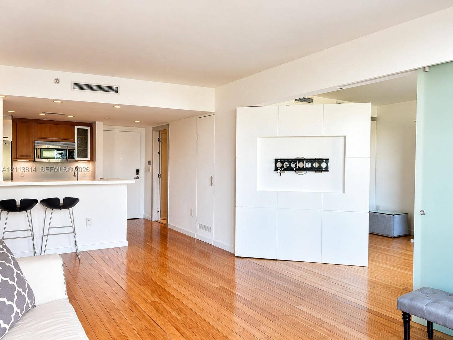 110 Washington Avenue, #1517, Miami Beach, Miami Beach, FL 33139 Hardwood flooring, wood cabinetry with stainless steel appliances, breakfast bar, recessed ceiling lighting, and a frosted glass sliding door