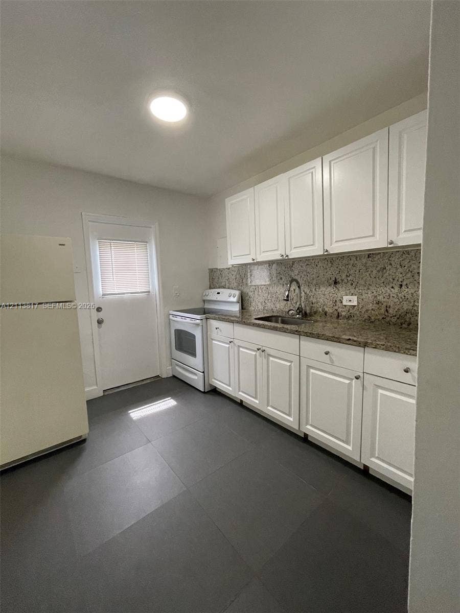 2515 NW 52nd Street, #1, Miami, Miami, FL 33142 Kitchen featuring white cabinetry, stone-surface countertops, tile flooring, and stainless steel hardware