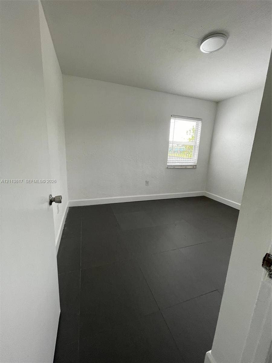2515 NW 52nd Street, #1, Miami, Miami, FL 33142 Neutral wall tones, dark tile flooring, a single-pane window, and a flush-mount overhead light fixture