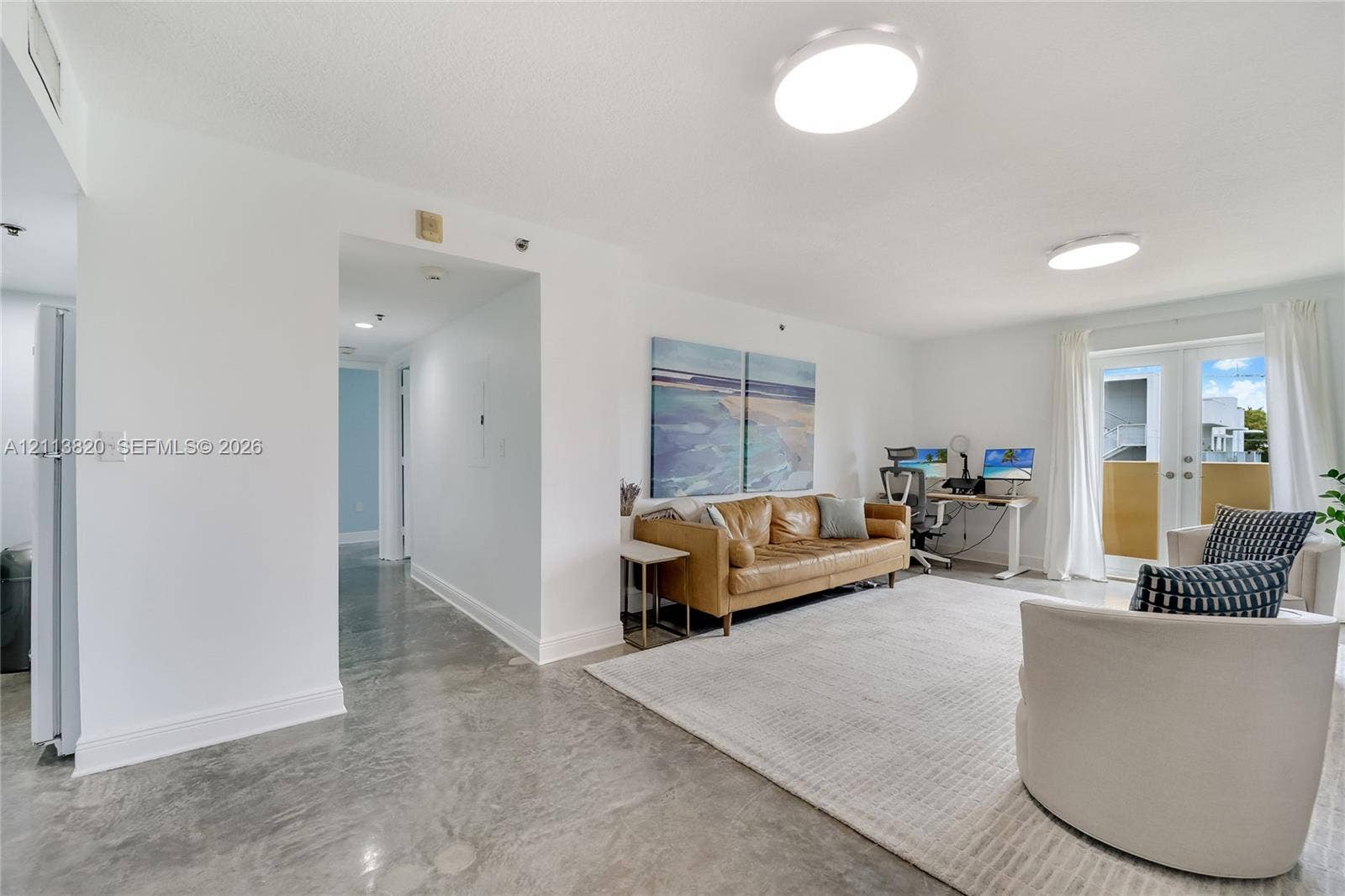 Polished concrete flooring, recessed lighting, and double glass-paned doors providing exterior access