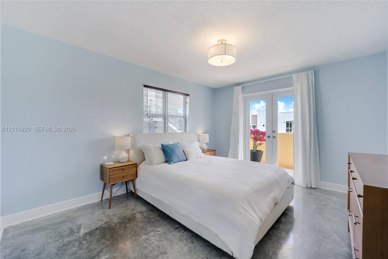 Polished concrete flooring, recessed window, glass-paneled double doors, and a central drum-style ceiling light fixture