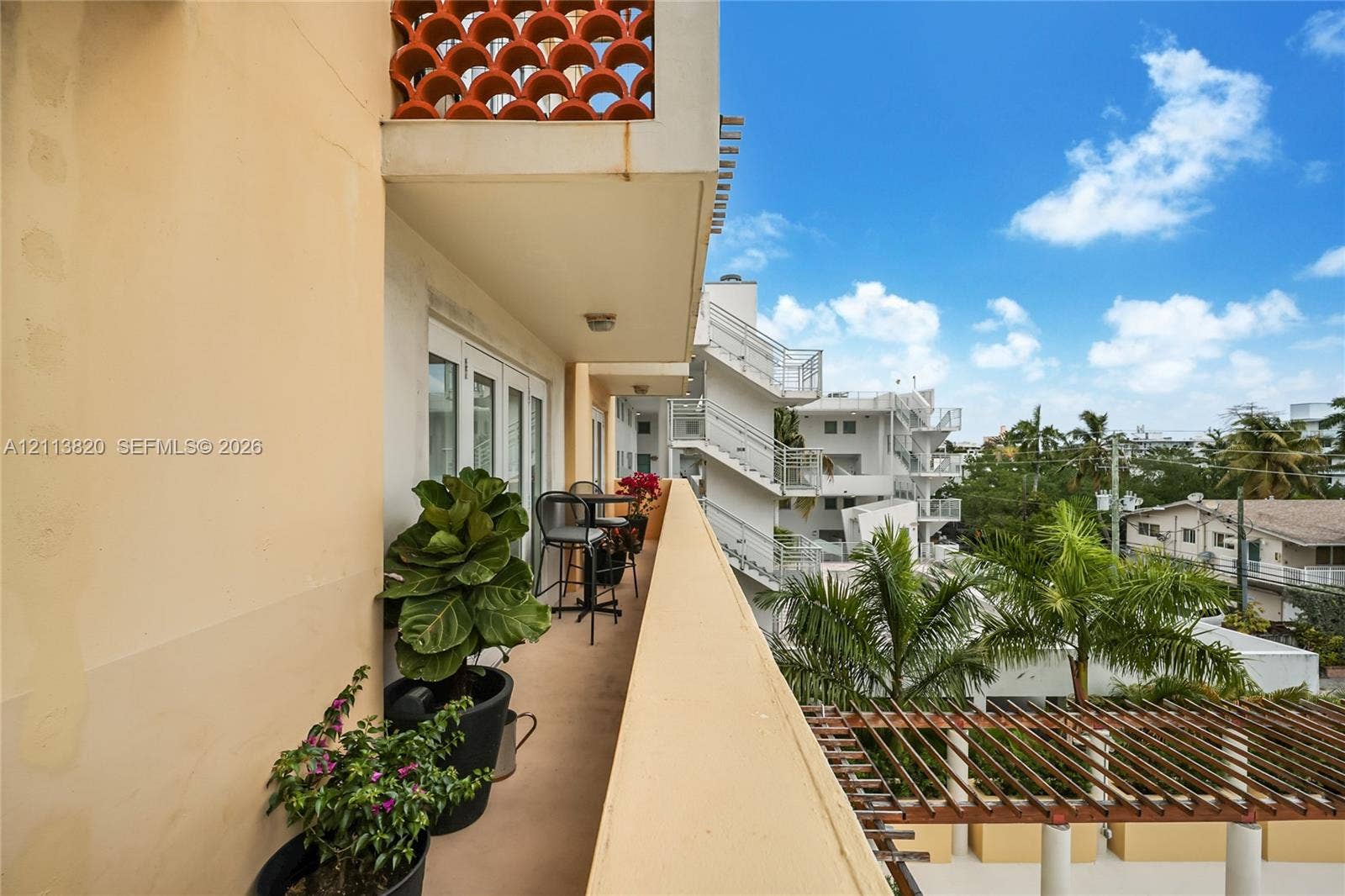 Private balcony featuring terracotta breeze block accents and a slatted timber pergola covering the area below