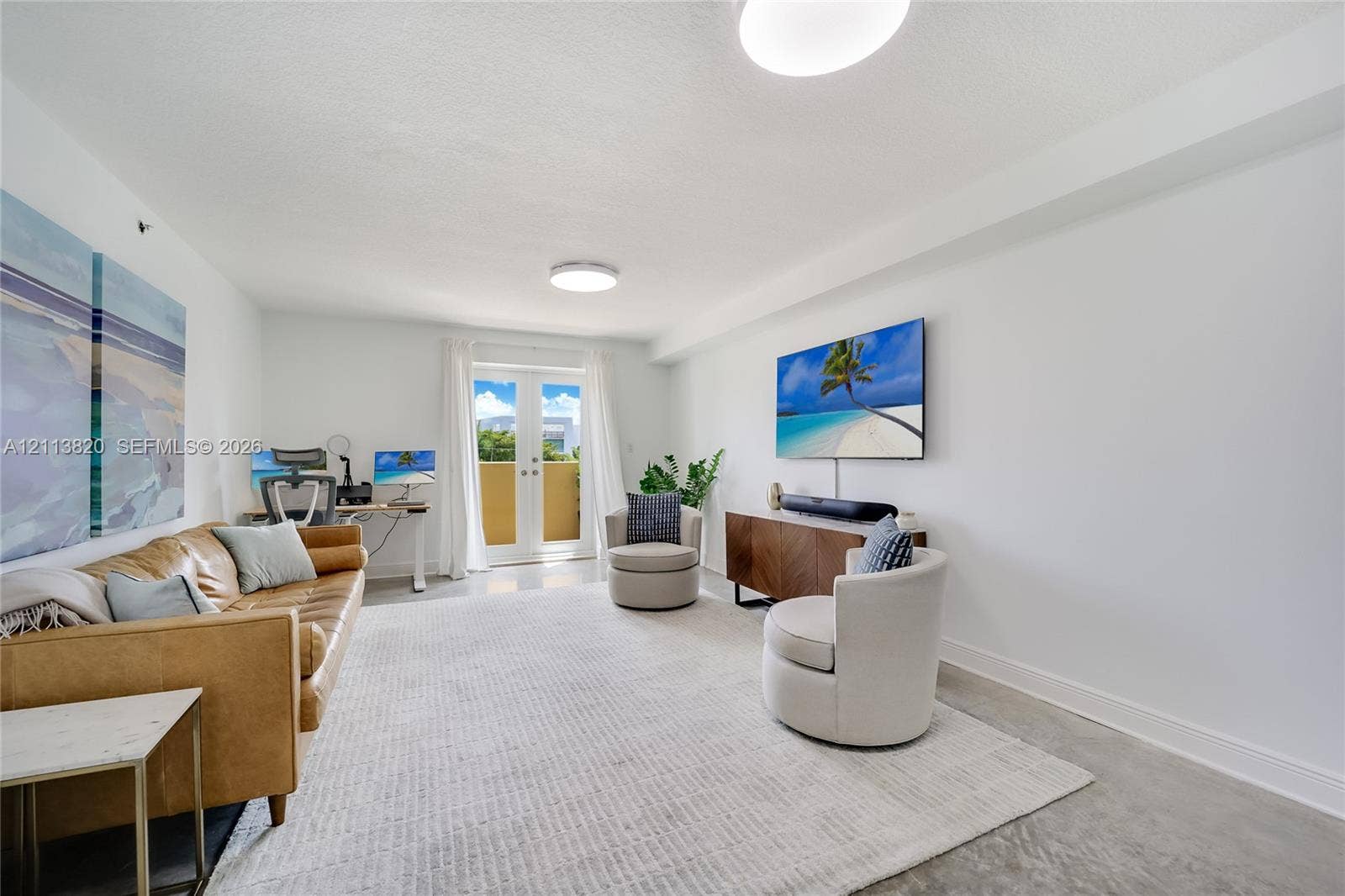 Neutral-toned interior space featuring polished concrete flooring, white walls, and French doors providing access to an exterior balcony