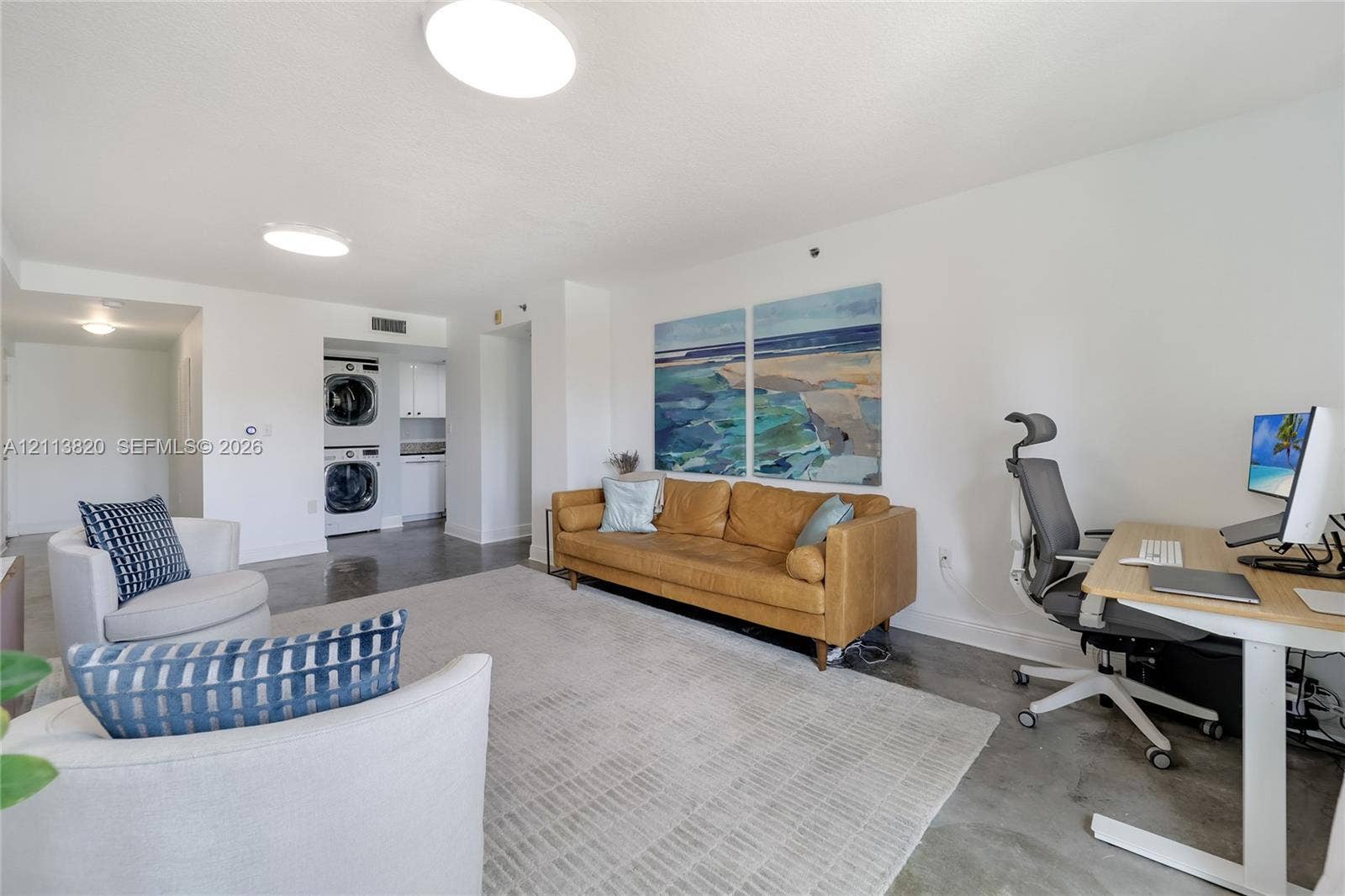 Open-concept interior featuring polished concrete flooring, recessed lighting, and a dedicated laundry area with stacked washer and dryer unit