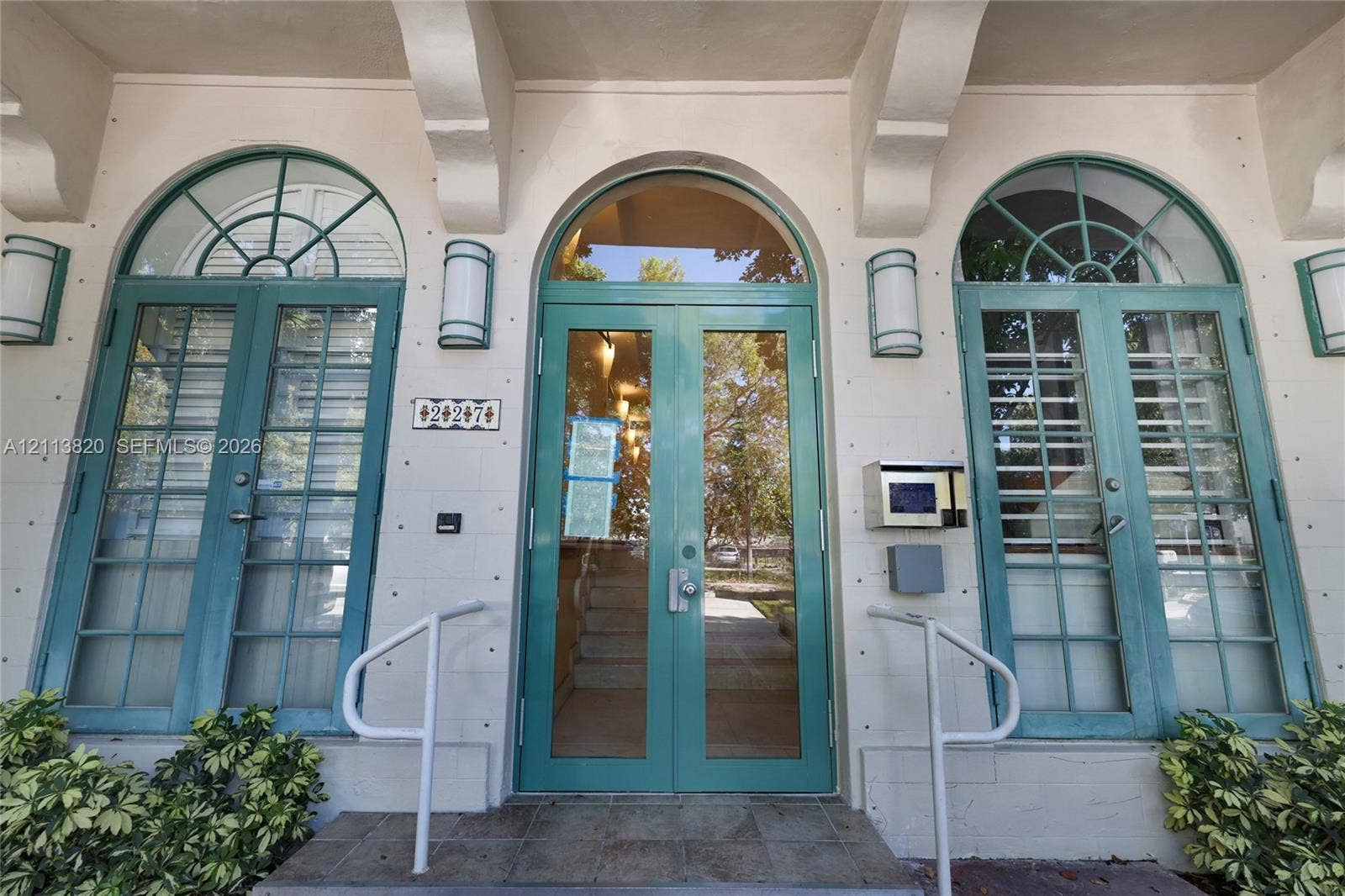 Mediterranean-style exterior featuring a symmetrical facade, ornate architectural detailing, multiple balconies with metal railings, a rooftop pergola, and arched window and doorway profiles