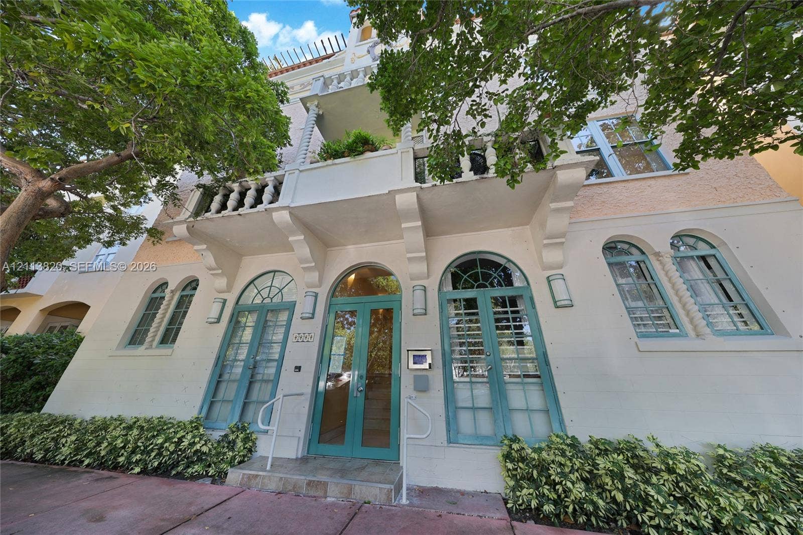 Exterior facade featuring arched windows with spiral column detailing, stone-textured masonry, and a cantilevered balcony with balustrade railings