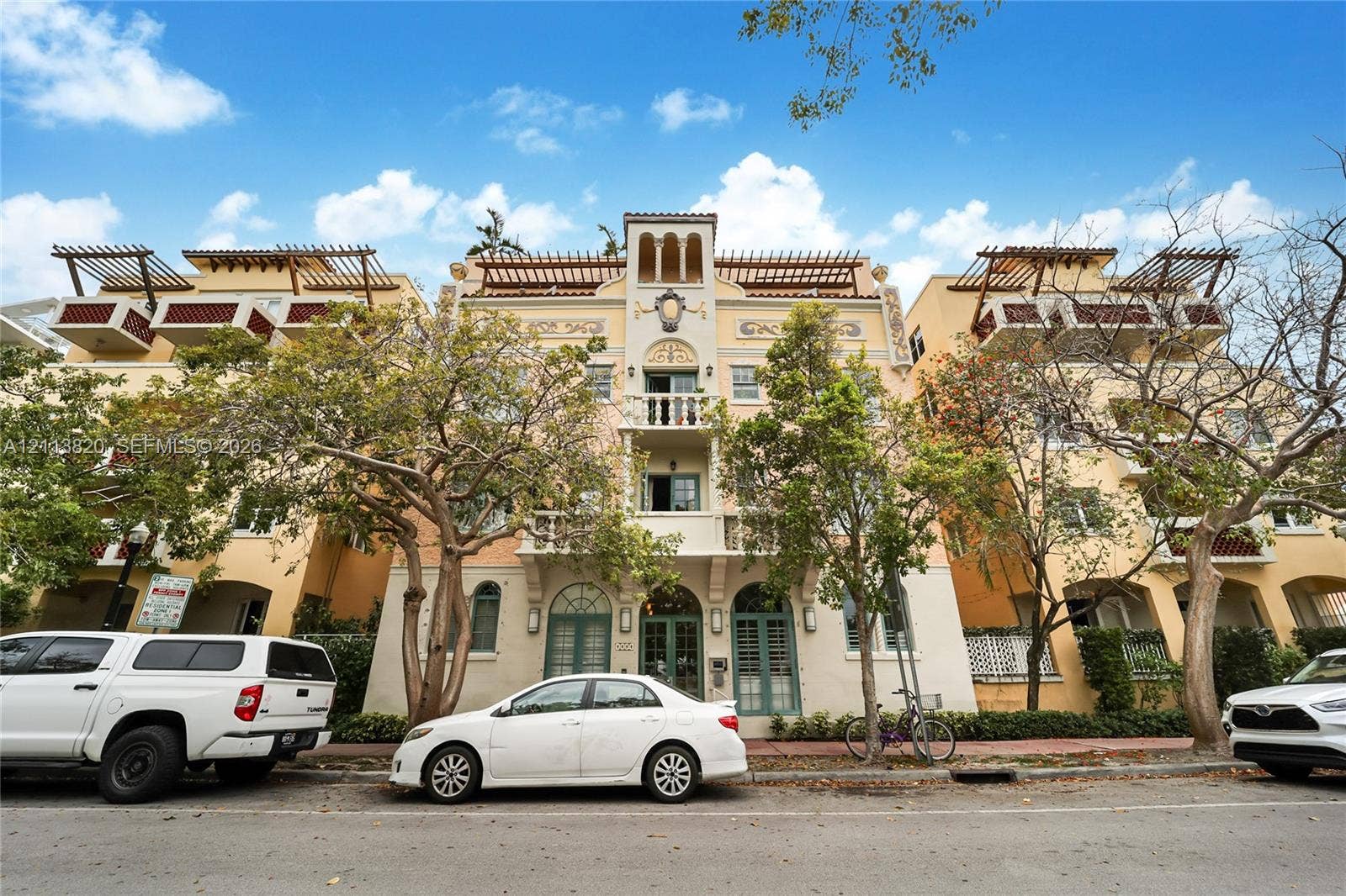 Multi-story exterior featuring a Mediterranean-inspired facade, arched architectural details, integrated balconies with metal railings, and rooftop pergolas