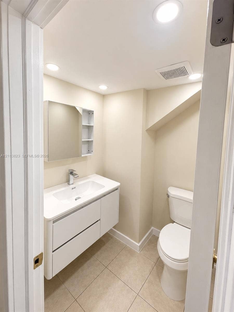 61 Matador Lane, #4-26, Davie, Davie, FL 33324 Modern floating vanity with a rectangular integrated sink, neutral stone-finish countertop, mirrored medicine cabinet with shelving, and tile flooring