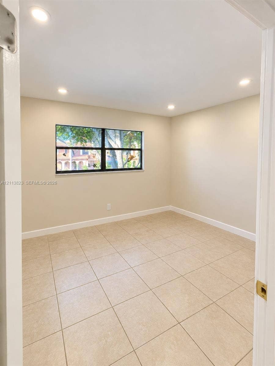 61 Matador Lane, #4-26, Davie, Davie, FL 33324 Neutral-toned interior featuring large-format ceramic floor tile, recessed ceiling lighting, and a single-pane window with a black frame