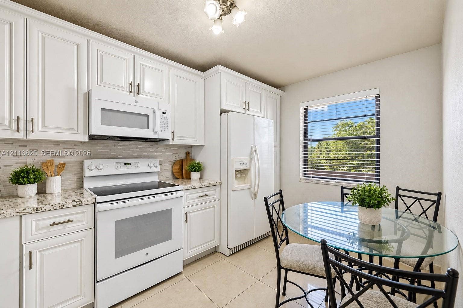 1200 NW 80th Avenue, #405A, Margate, FL 33063 Kitchen featuring white cabinetry, stone-finish countertops, tile backsplash, white appliances, and ceramic tile flooring