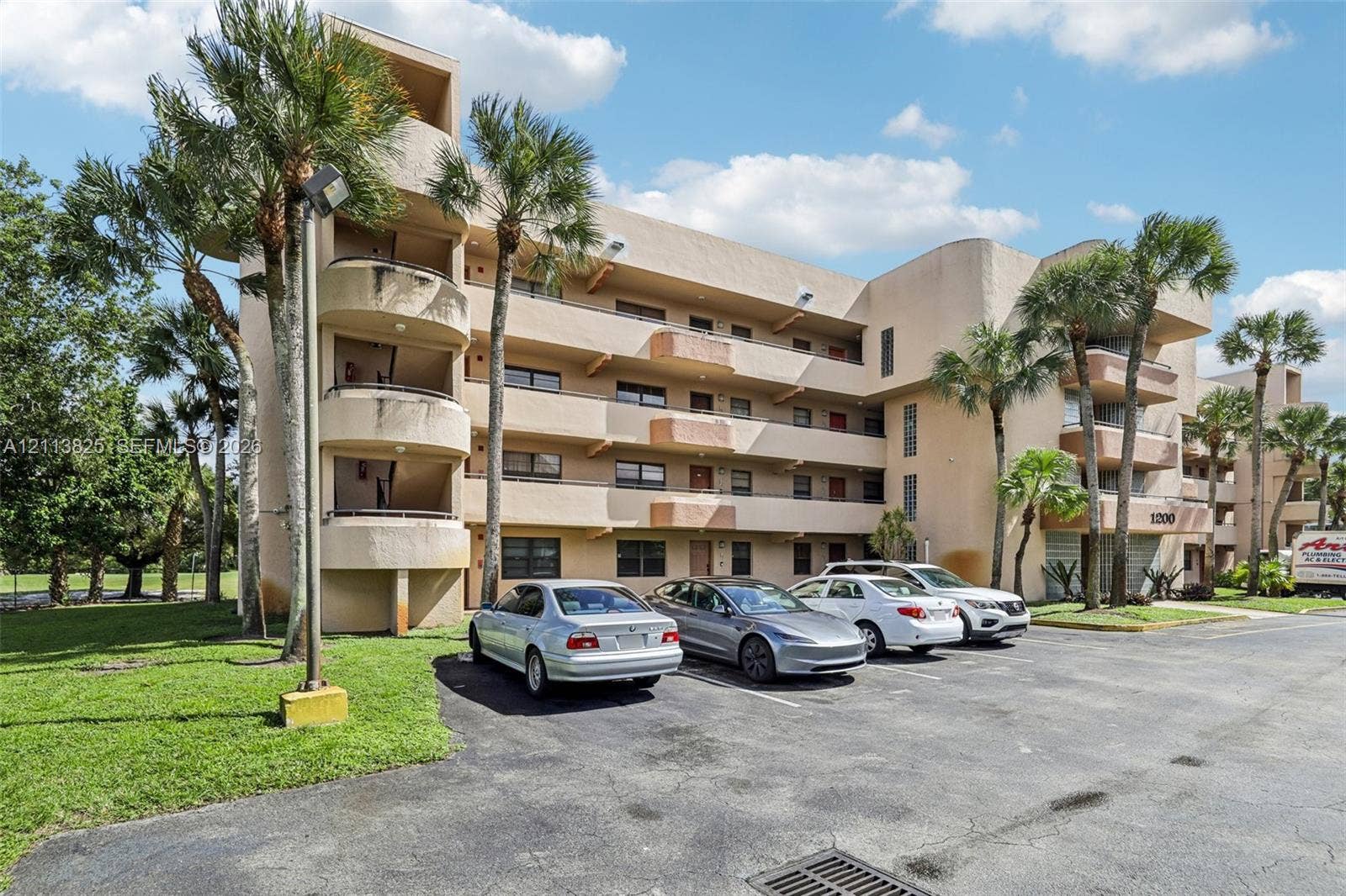 1200 NW 80th Avenue, #405A, Margate, FL 33063 Multi-story residential building featuring stucco exterior, private curved balconies, and mature palm tree landscaping