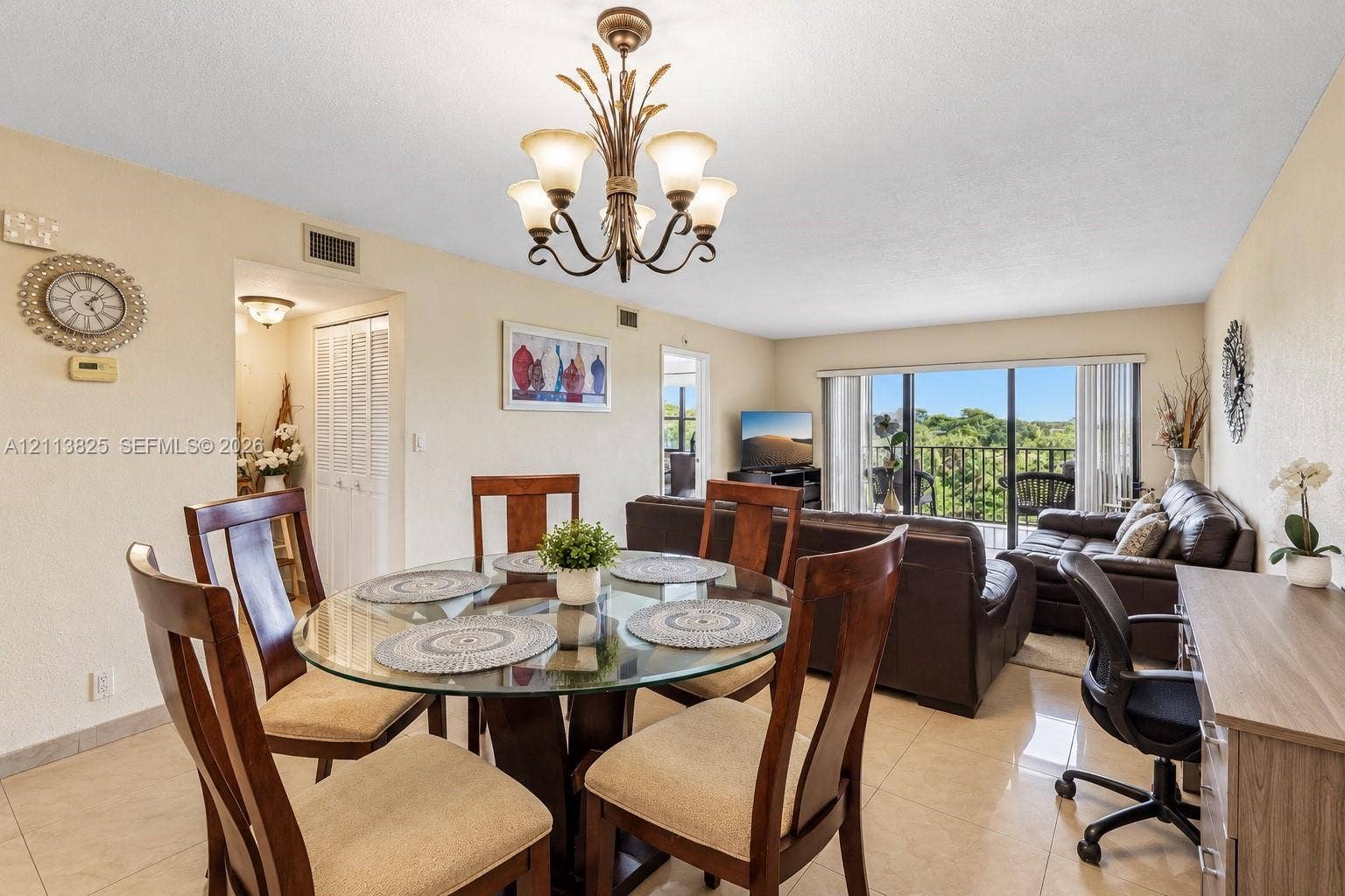 1200 NW 80th Avenue, #405A, Margate, FL 33063 Open-concept floor plan featuring large-format tile flooring, a multi-arm decorative chandelier, and sliding glass doors with access to an exterior balcony
