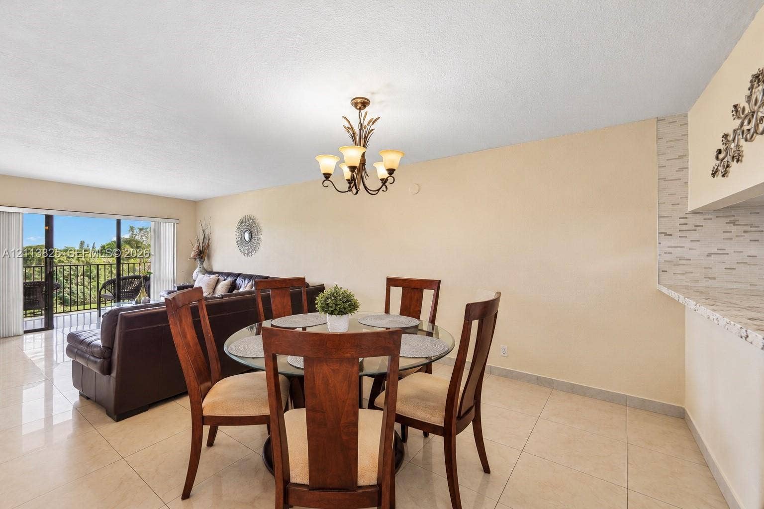 1200 NW 80th Avenue, #405A, Margate, FL 33063 Open-concept area featuring tile flooring, a multi-arm chandelier, and a breakfast bar with stone-finish surfacing and decorative tile backsplash