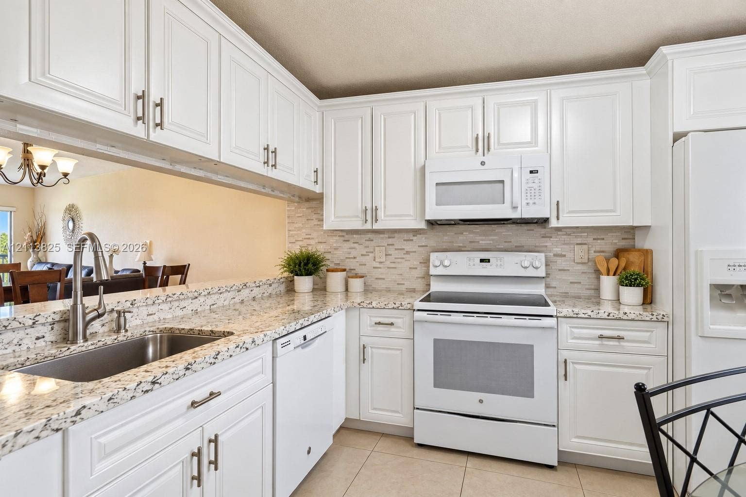 1200 NW 80th Avenue, #405A, Margate, FL 33063 Kitchen featuring white shaker-style cabinetry, speckled stone countertops, a subway tile backsplash, and stainless steel undermount sink