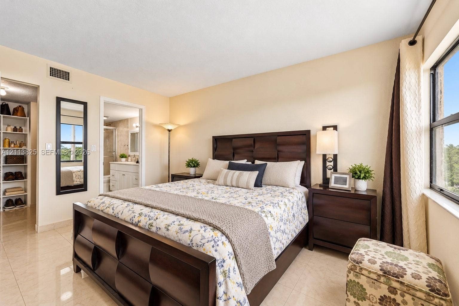 1200 NW 80th Avenue, #405A, Margate, FL 33063 Spacious room featuring neutral tile flooring, a wall-mounted rectangular mirror with a dark frame, and a walk-in storage area with built-in shelving