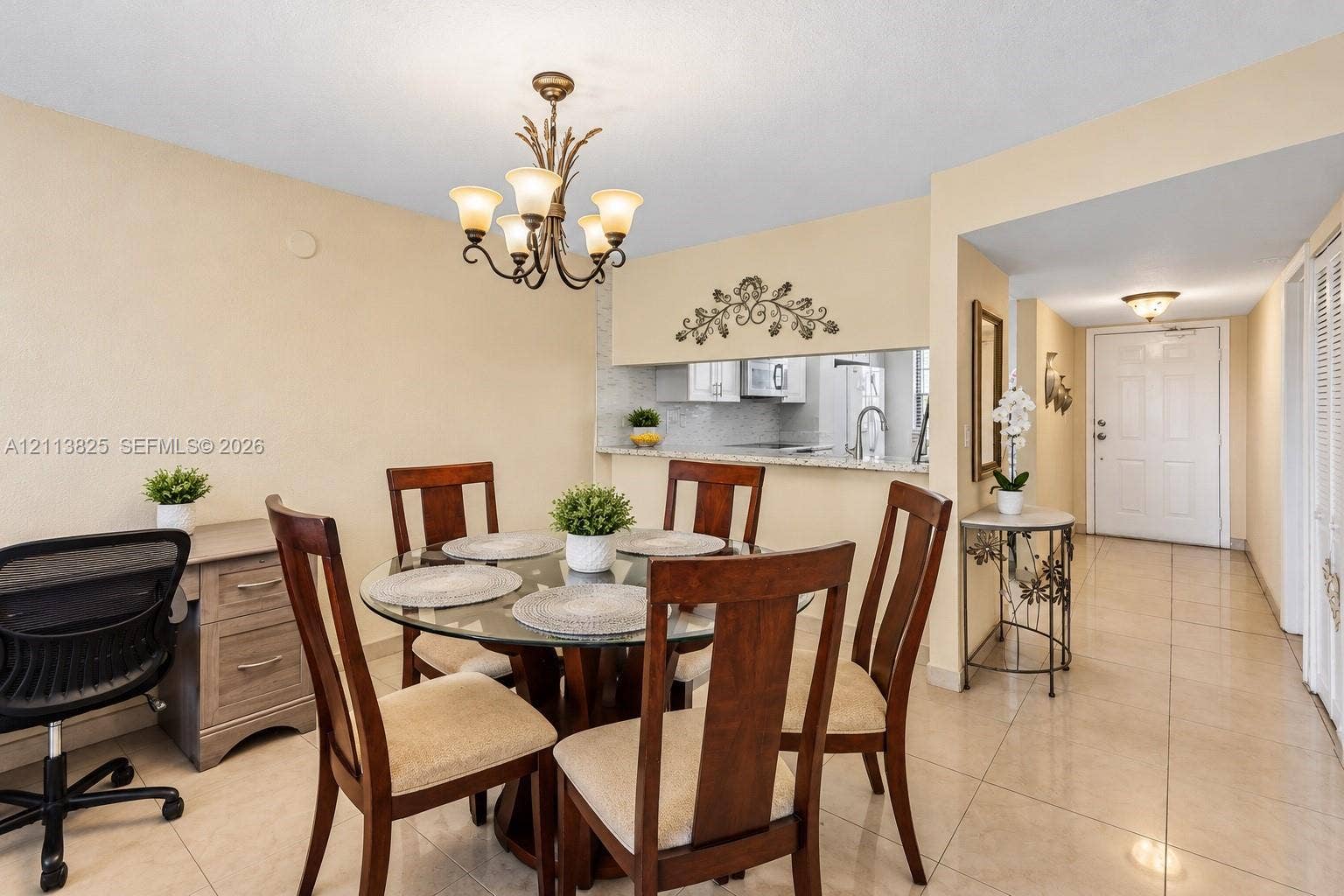 1200 NW 80th Avenue, #405A, Margate, FL 33063 Neutral tile flooring, decorative multi-arm chandelier, and open-concept pass-through window with solid-surface countertop