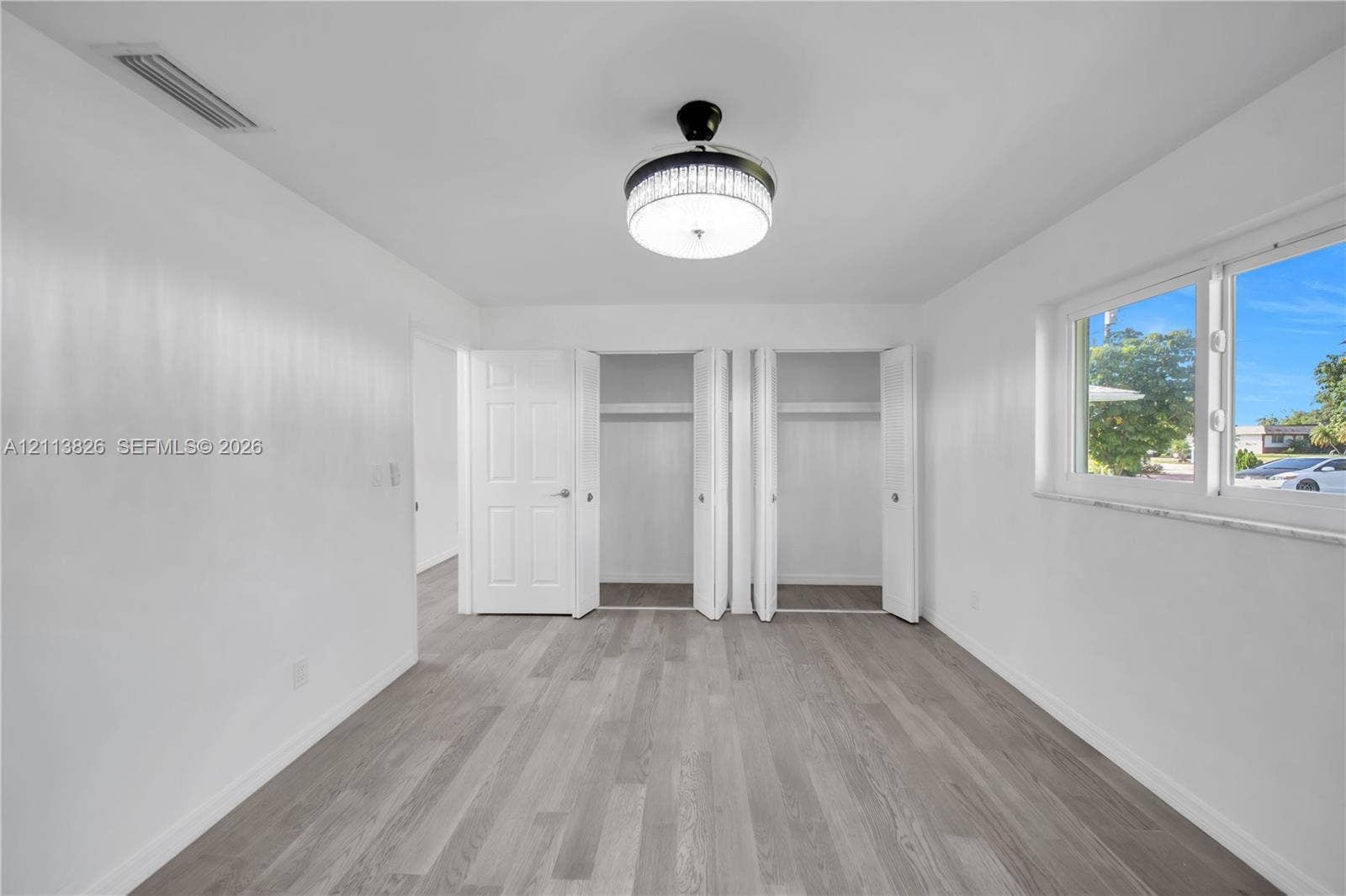 1206 NE 4th Terrace, Cape Coral, Cape Coral, FL 33909 Room featuring wood-finish flooring, dual bi-fold closets, and a central drum-style ceiling fixture