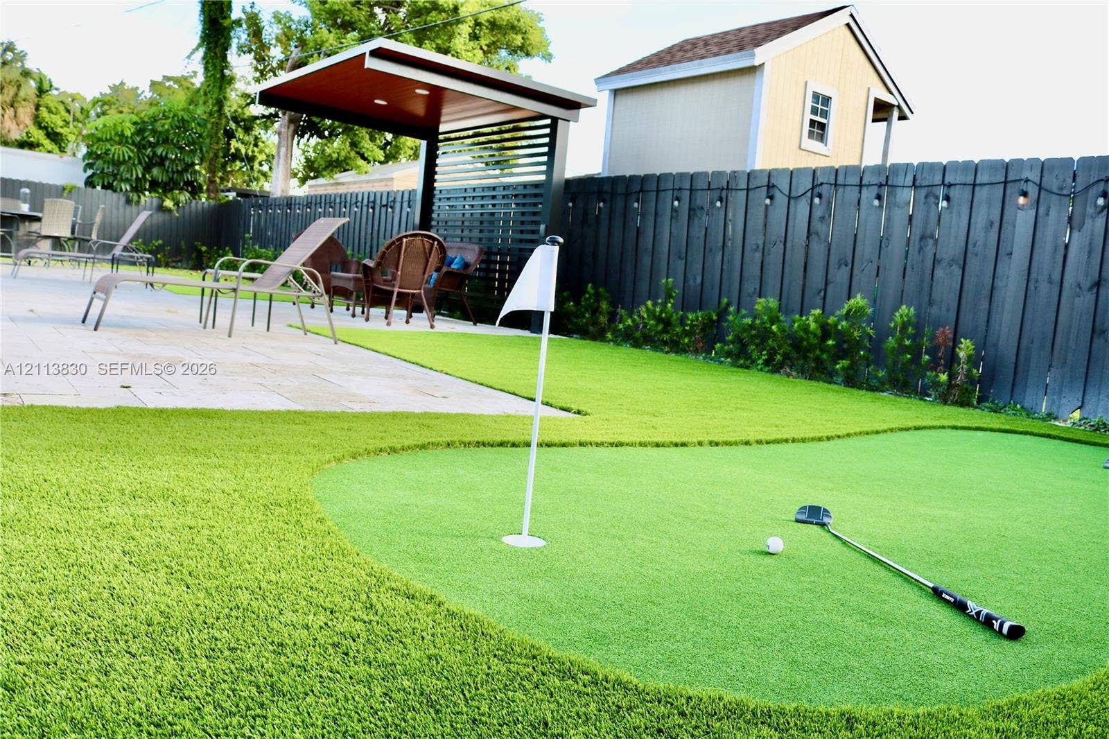 3545 SW 104th Court, Miami, FL 33165 Outdoor putting green featuring synthetic turf, paver patio, covered pavilion with slatted privacy screen, and fenced perimeter