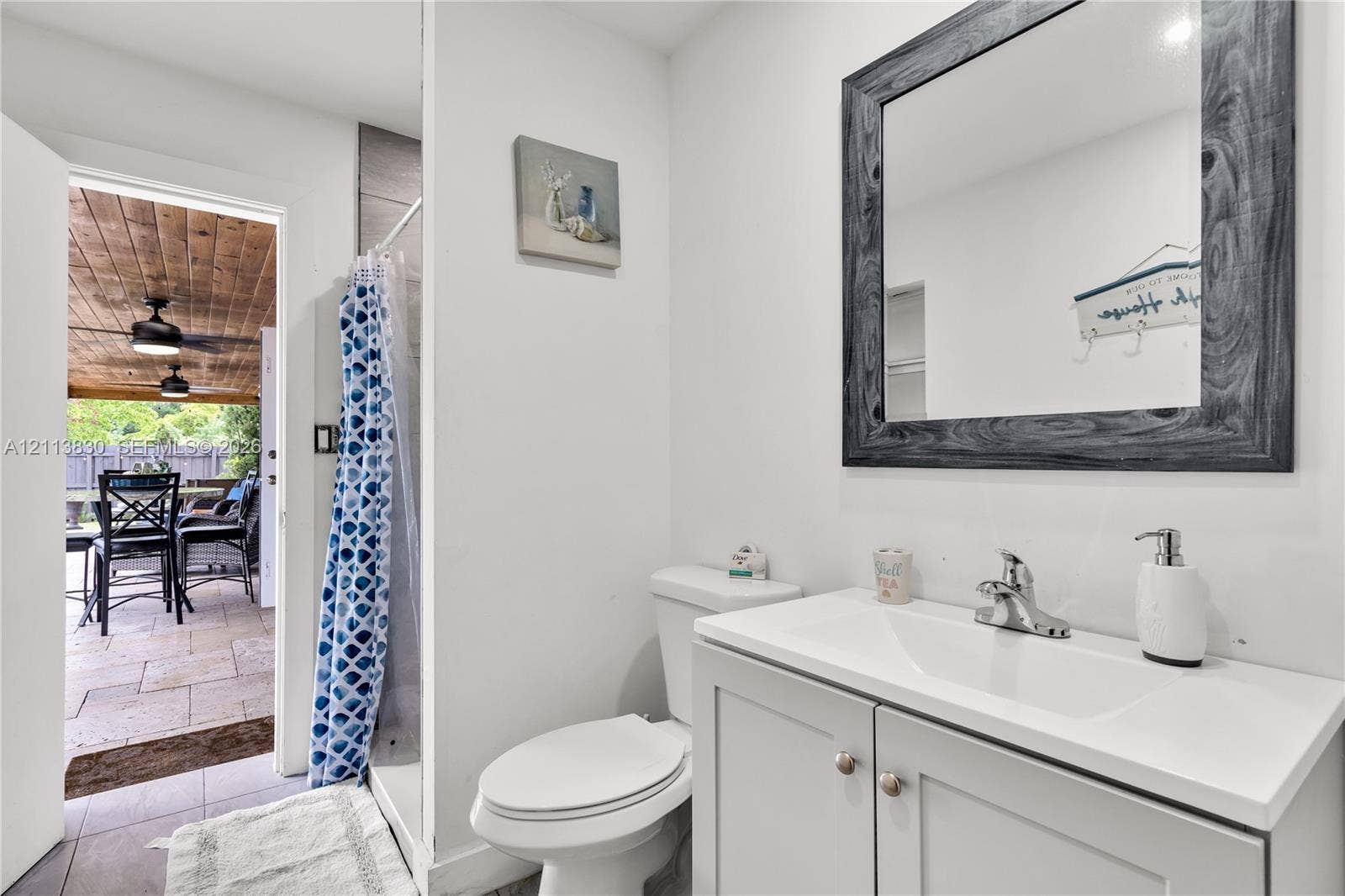 3545 SW 104th Court, Miami, FL 33165 Bathroom featuring a gray shaker-style vanity with a white countertop and integrated sink, chrome faucet, and a wall-mounted mirror with a distressed gray wood-finish frame