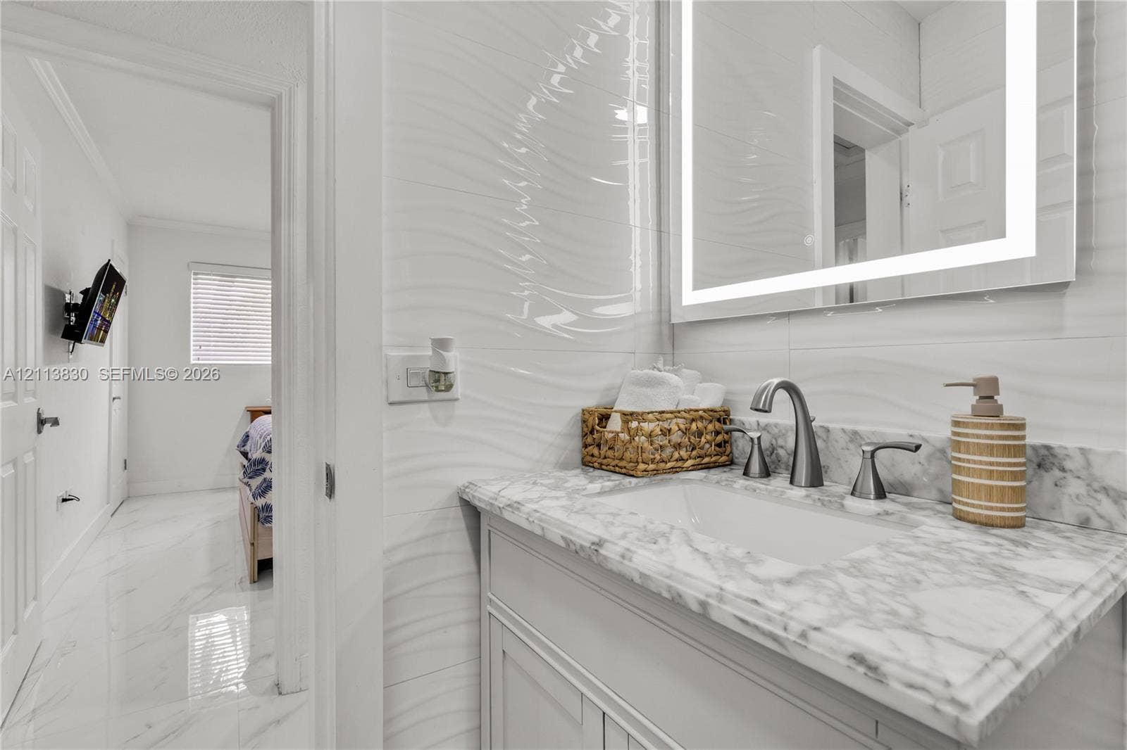 3545 SW 104th Court, Miami, FL 33165 Vanity featuring stone-finish countertop, undermount sink, brushed nickel faucet, integrated LED mirror, and textured wall tiling