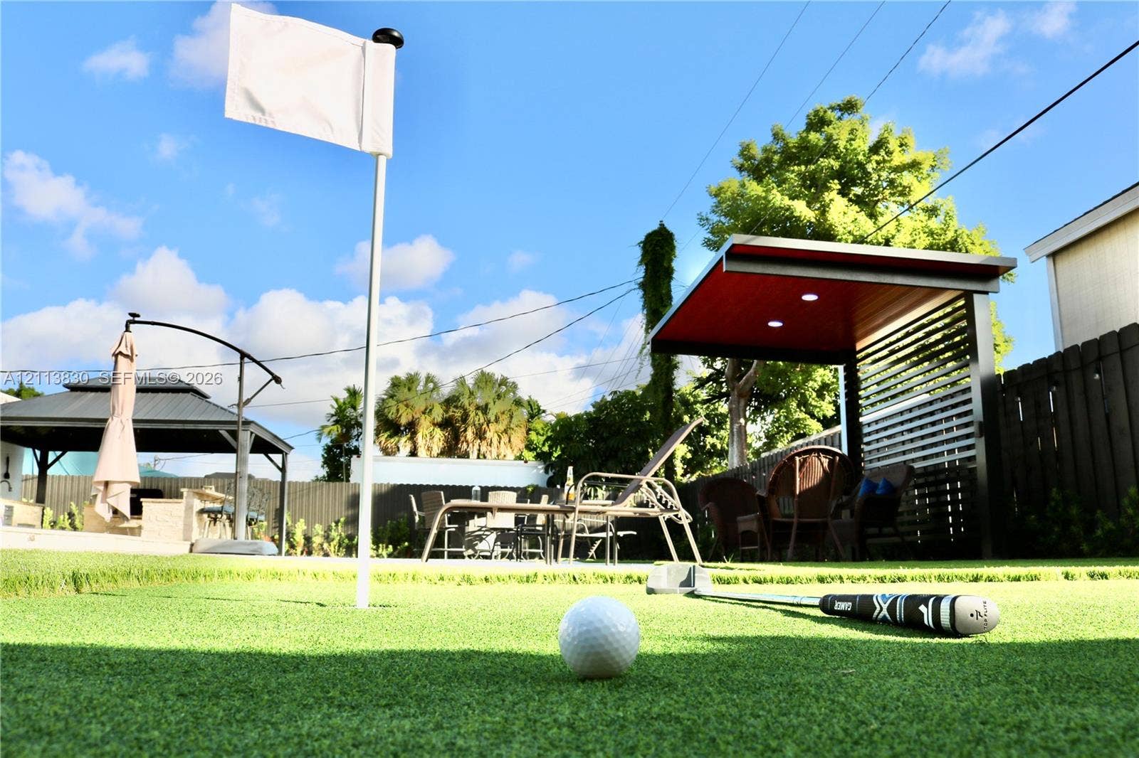 3545 SW 104th Court, Miami, FL 33165 Backyard putting green with integrated flag pole, covered patio structure with slatted privacy screen, and recessed ceiling lighting