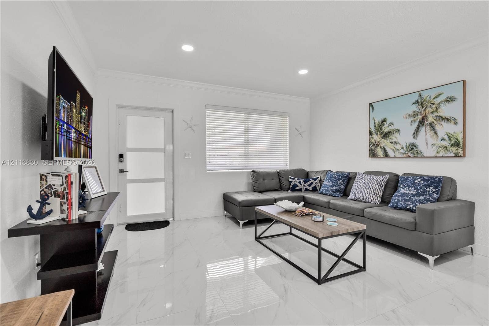 3545 SW 104th Court, Miami, FL 33165 Bright living space featuring high-gloss large-format tile flooring, recessed lighting, and a frosted glass-paneled entry door