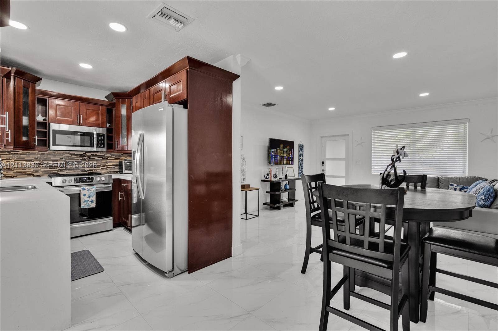 3545 SW 104th Court, Miami, FL 33165 Kitchen featuring stained wood cabinetry, stainless steel appliances, multi-tonal linear tile backsplash, and white polished flooring