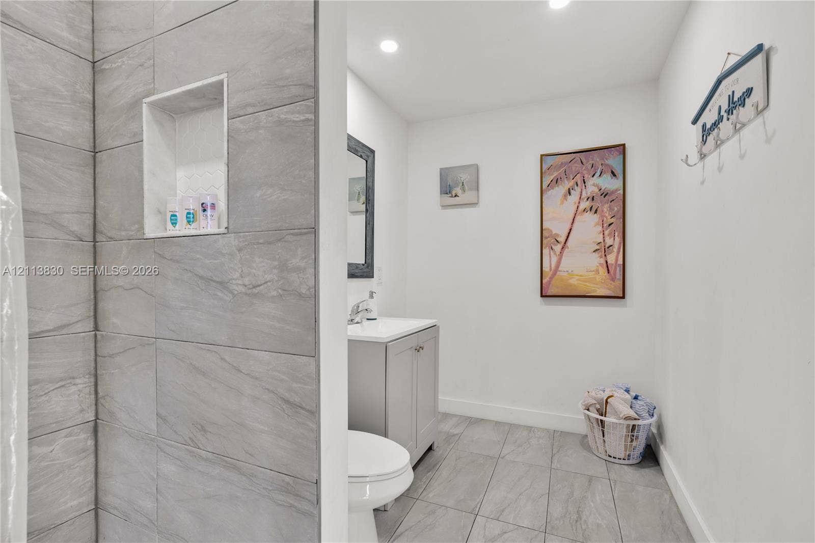 3545 SW 104th Court, Miami, FL 33165 Bathroom featuring large-format grey tile shower surround with integrated wall niche, light grey vanity cabinet, solid-surface countertop, and ceramic floor tiling