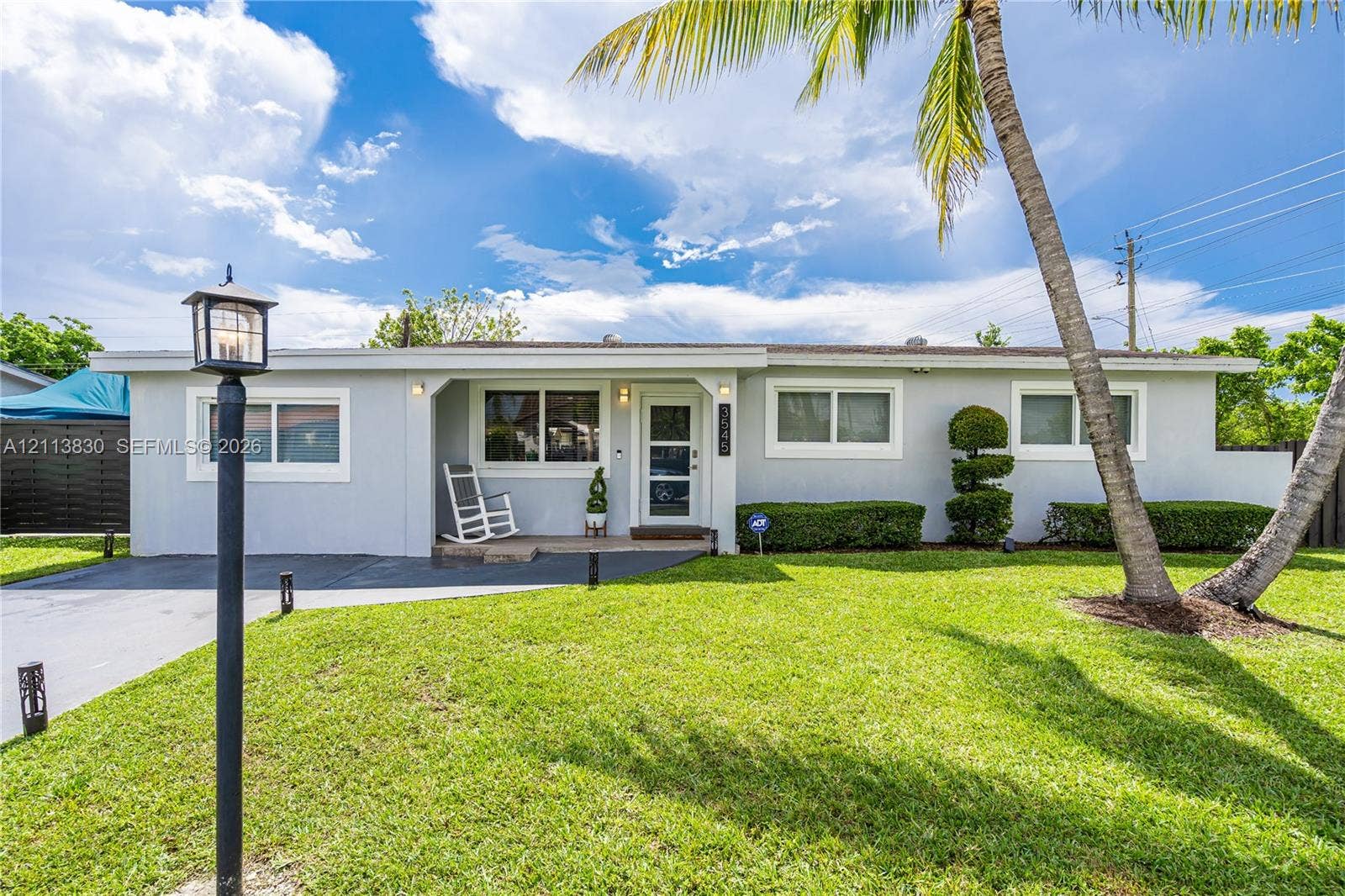 3545 SW 104th Court, Miami, FL 33165 Single-story residence featuring a light-toned exterior, concrete driveway, covered front entryway, and manicured landscaping