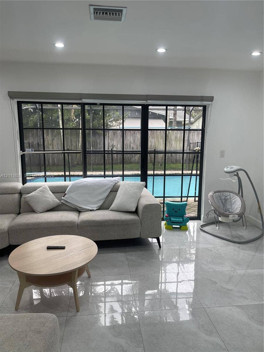 10153 SW 51st Street, Cooper City, Cooper City, FL 33328 Large-format tile flooring, recessed ceiling lighting, and expansive black-framed grid windows featuring a pool exterior
