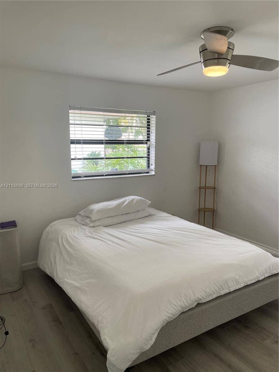 10153 SW 51st Street, Cooper City, Cooper City, FL 33328 Neutral interior featuring wood-finish flooring, a horizontal window with adjustable blinds, and a ceiling-mounted fan with integrated lighting