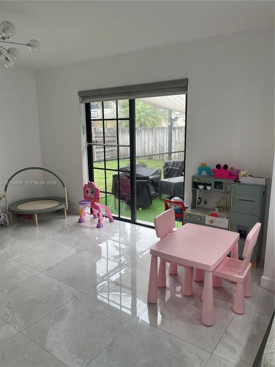 10153 SW 51st Street, Cooper City, Cooper City, FL 33328 Large-format polished tile flooring, sliding glass door with black grid frames, and modern multi-arm chandelier