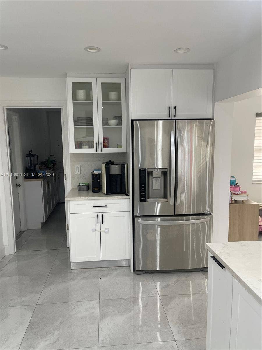 10153 SW 51st Street, Cooper City, Cooper City, FL 33328 Kitchen featuring white shaker-style cabinetry with glass-front uppers, stainless steel refrigerator, stone-composite countertops, and large-format porcelain tile flooring