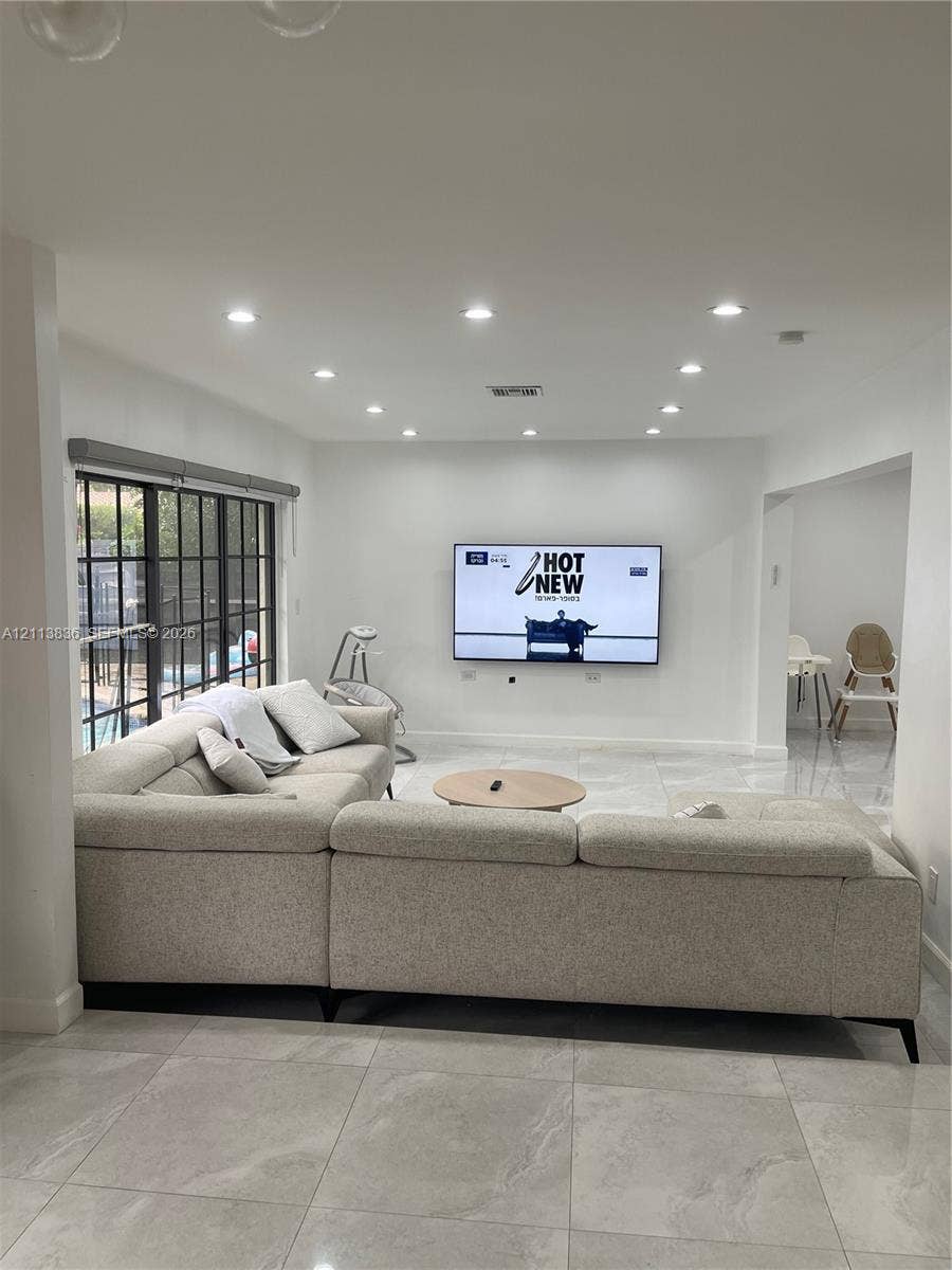 10153 SW 51st Street, Cooper City, Cooper City, FL 33328 Open-concept living space featuring large-format tile flooring, recessed lighting, and expansive floor-to-ceiling windows with dark mullions