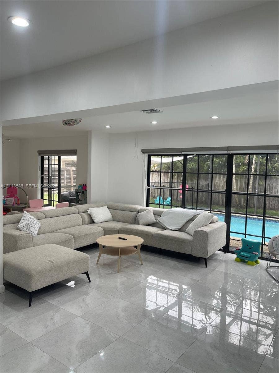 10153 SW 51st Street, Cooper City, Cooper City, FL 33328 Polished stone-finish flooring, recessed lighting, and black-framed glass sliding doors opening to an exterior swimming pool