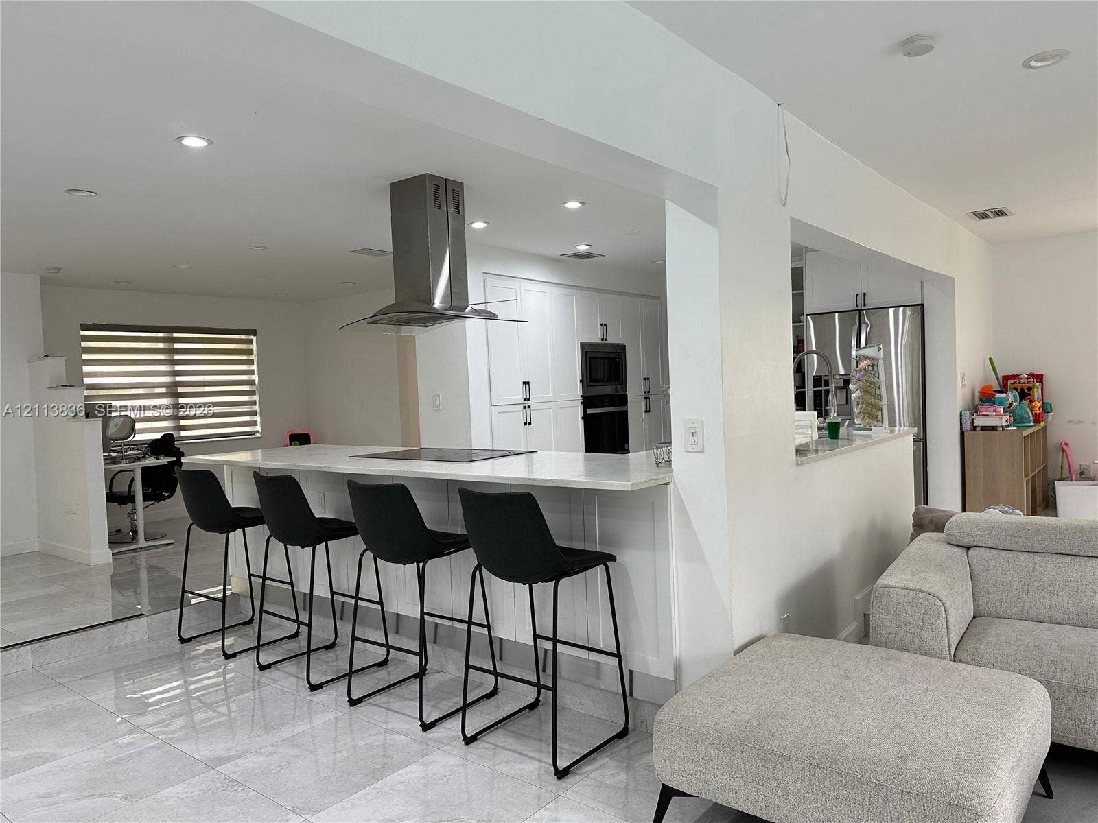 10153 SW 51st Street, Cooper City, Cooper City, FL 33328 Open-concept kitchen featuring an expansive center island with stone countertop, stainless steel ceiling-mounted range hood, built-in wall oven, and large-format tile flooring