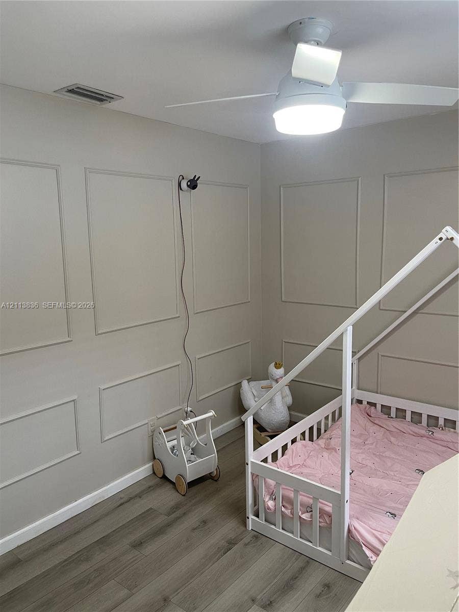 10153 SW 51st Street, Cooper City, Cooper City, FL 33328 Room featuring neutral-toned wall molding, wood-finish flooring, and a ceiling-mounted fan with integrated lighting