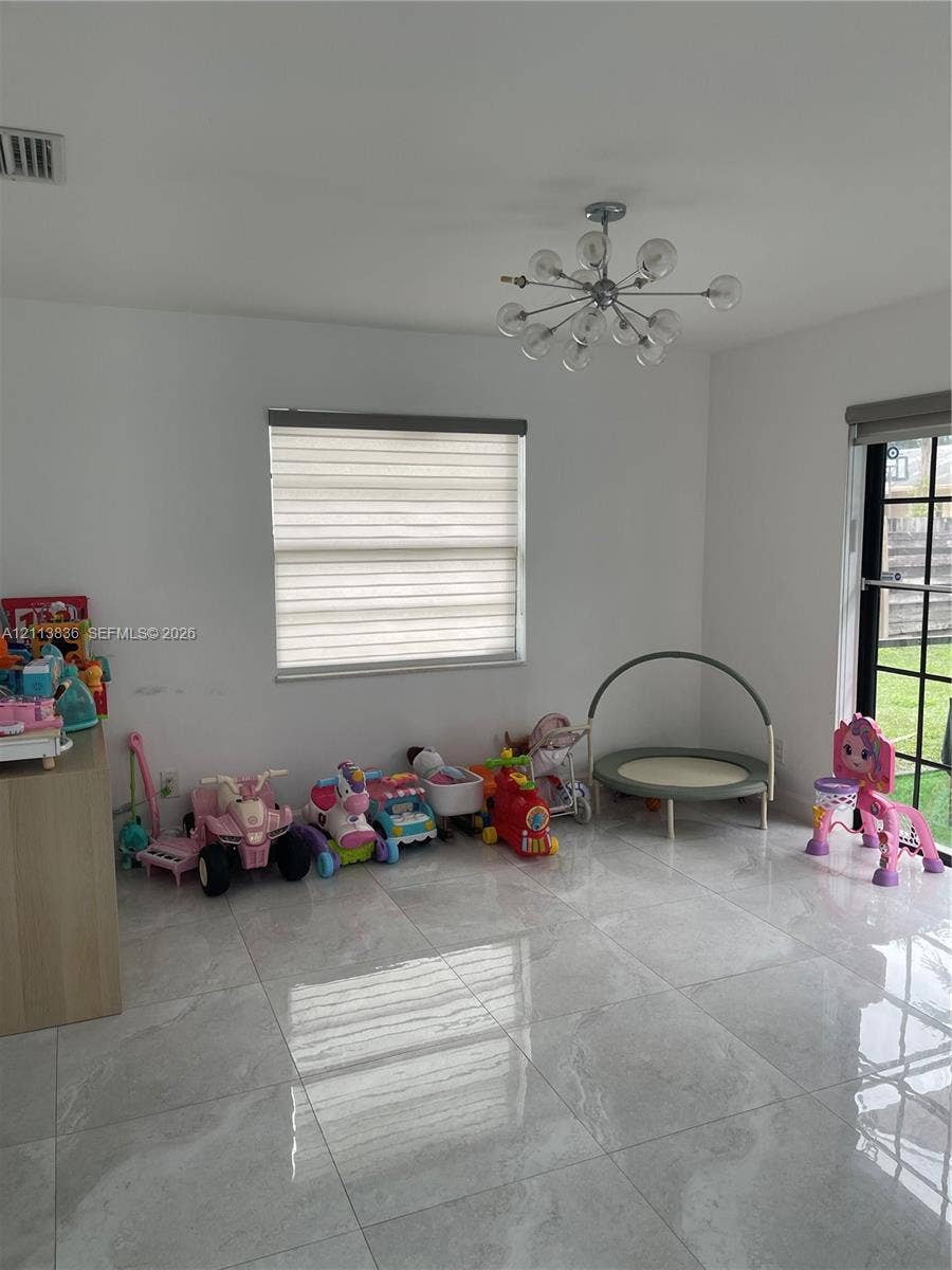 10153 SW 51st Street, Cooper City, Cooper City, FL 33328 Interior space featuring polished stone-finish flooring, a contemporary multi-arm sputnik chandelier, dual-tone roller shades, and a full-height glass paneled door