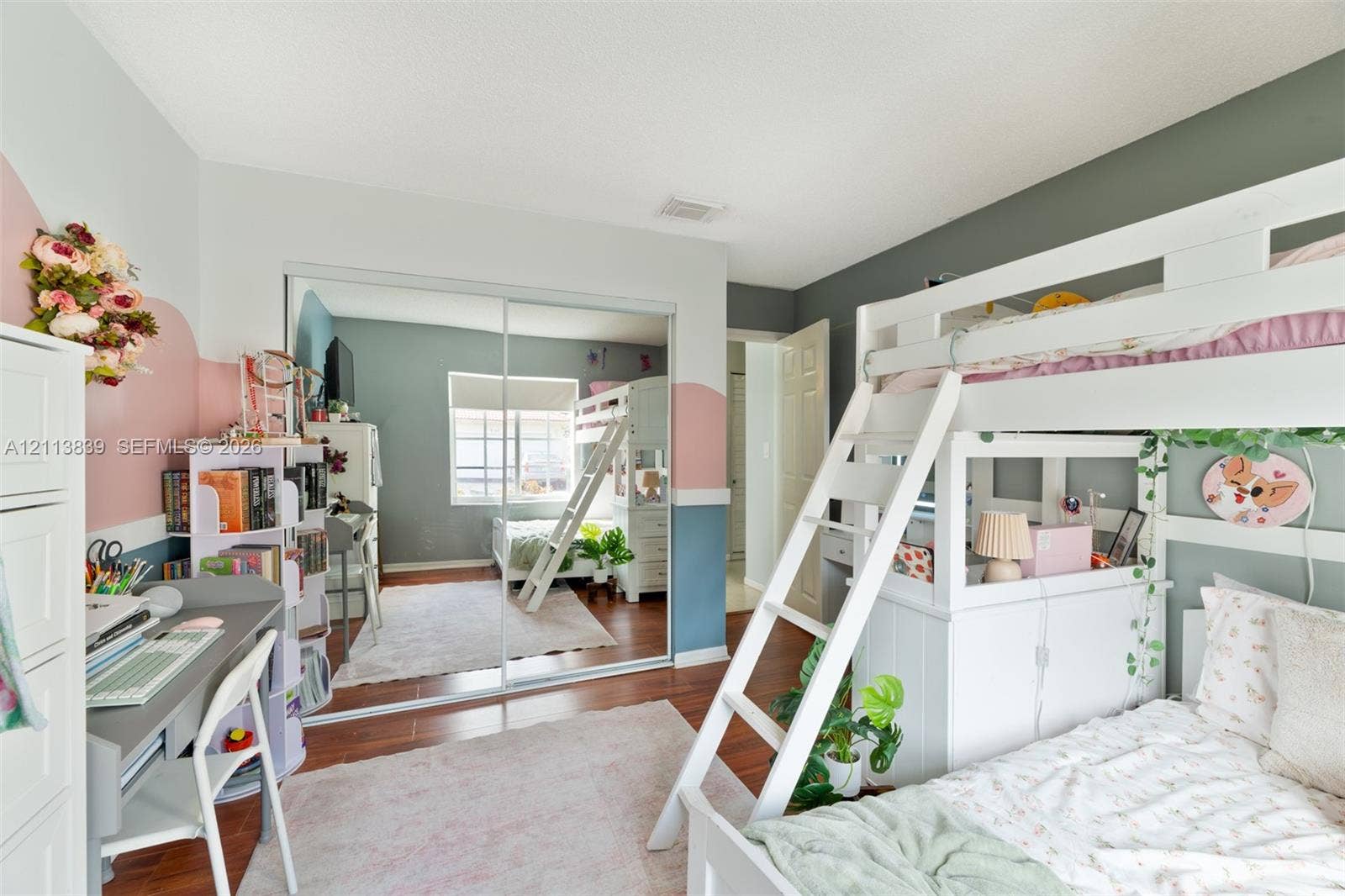 1015 NW 124th Terrace, Sunrise, FL 33323 Room with wood-finish flooring, sliding mirror-panel closet doors, and neutral wall color palette