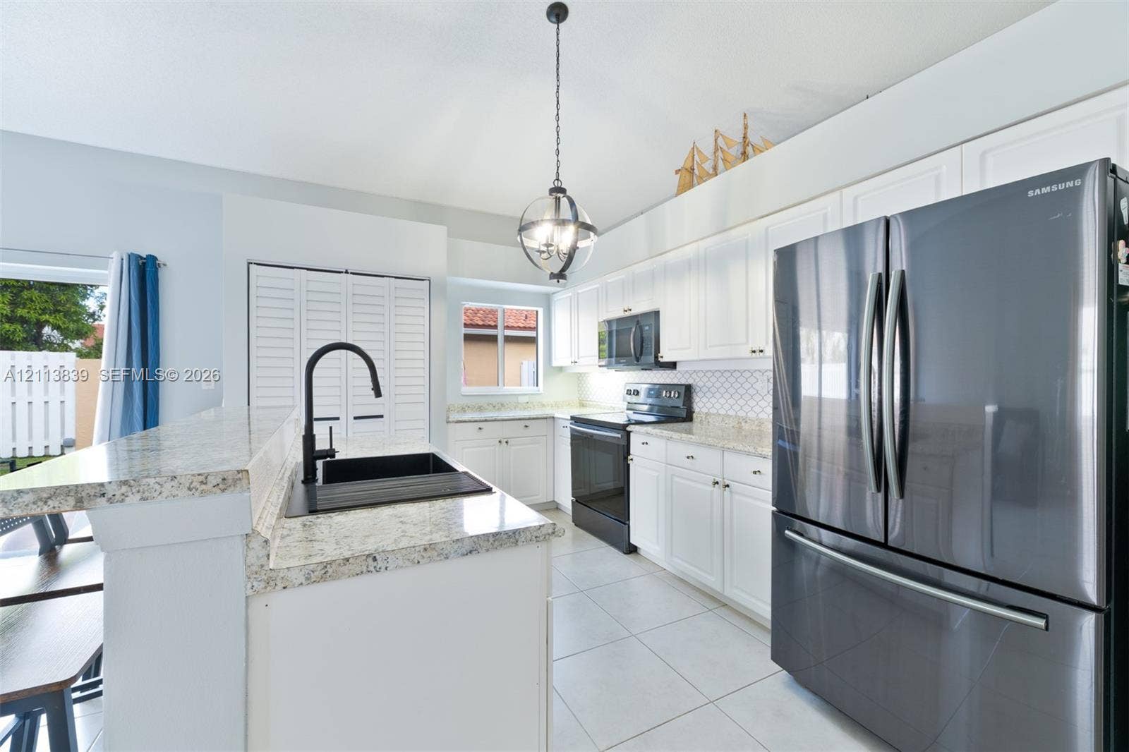 1015 NW 124th Terrace, Sunrise, FL 33323 Kitchen featuring white cabinetry, stone-finish countertops, stainless steel appliances, a matte black faucet, and an overhead pendant light fixture