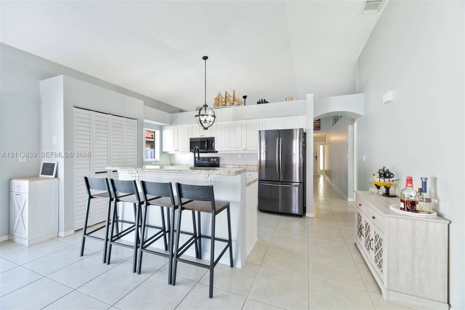 1015 NW 124th Terrace, Sunrise, FL 33323 Kitchen featuring white cabinetry, stone countertops, stainless steel appliances, a center island with a stone-top breakfast bar, and tile flooring