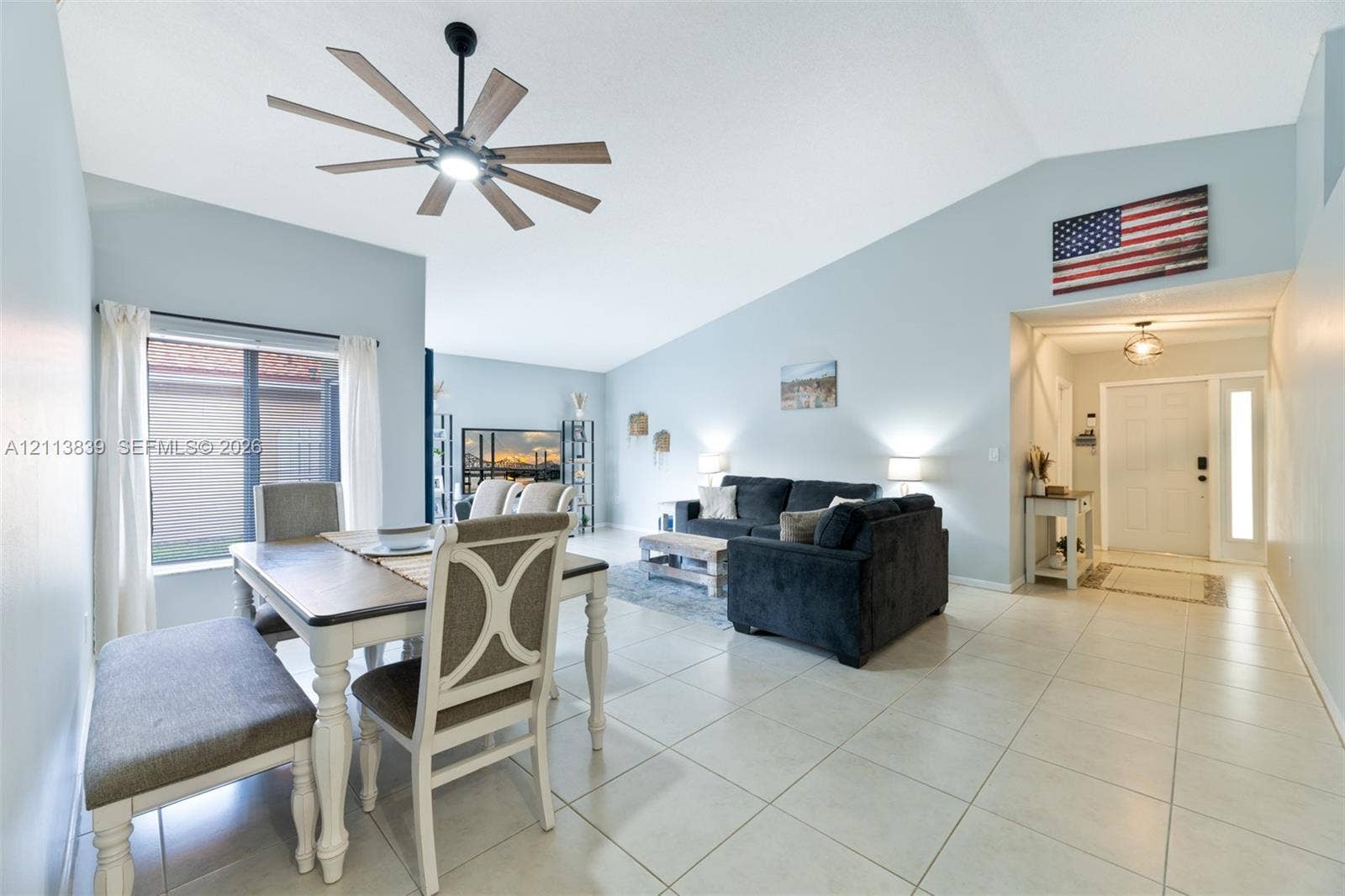 1015 NW 124th Terrace, Sunrise, FL 33323 Vaulted ceilings, large-format tile flooring, multi-blade ceiling fan with integrated lighting, and a front entry door featuring a vertical glass sidelight